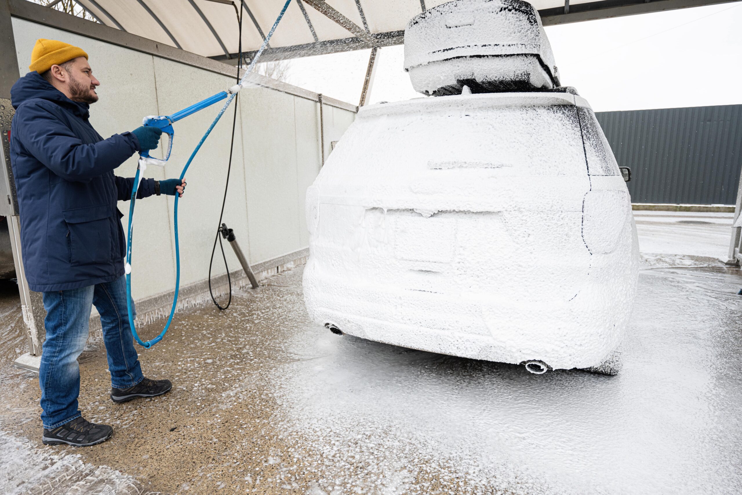 Man washing an SUV with a roof rack at a car wash