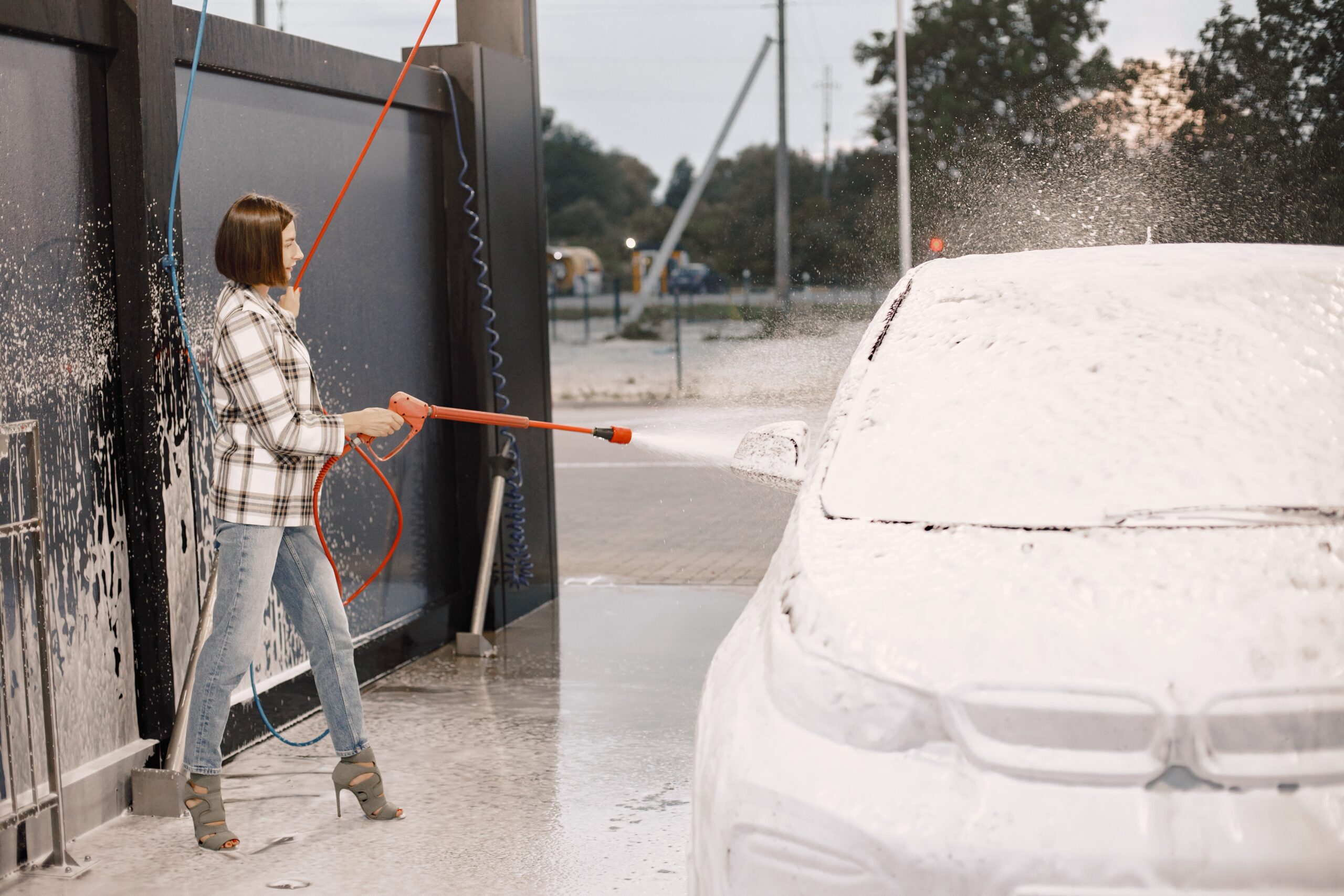Woman washing her car in a self-serve car wash bay