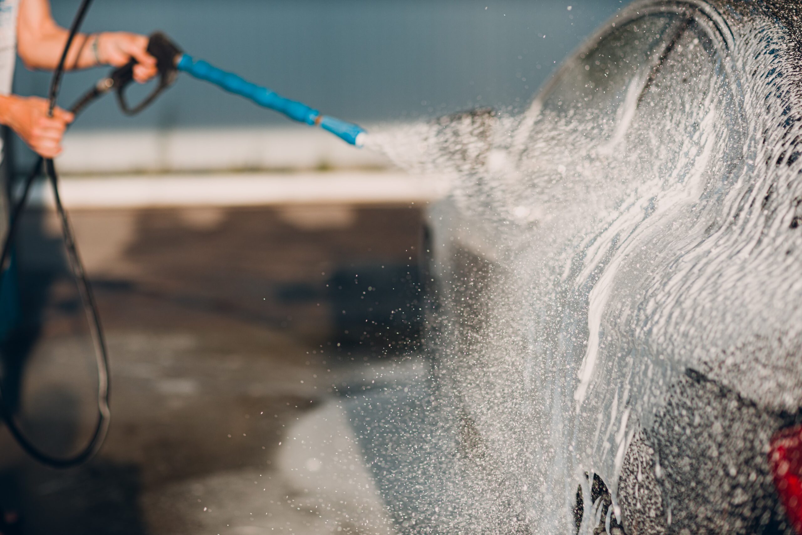Worker washing a car at a self-service car wash